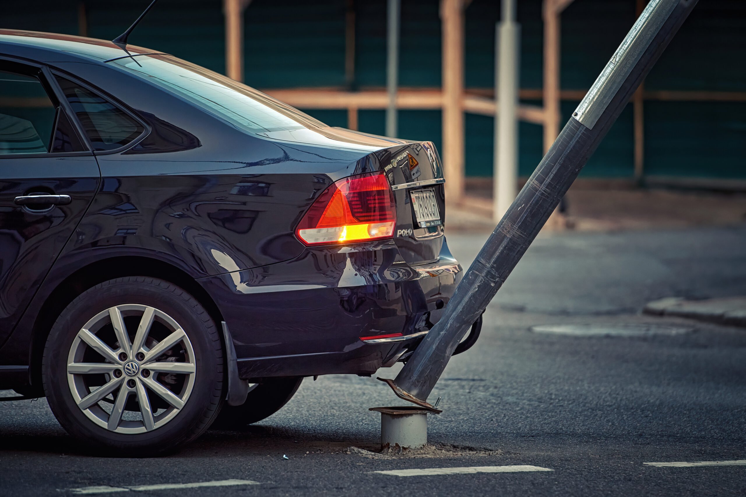 Car hit pole with traffic lights and pedestrian crossing sign.