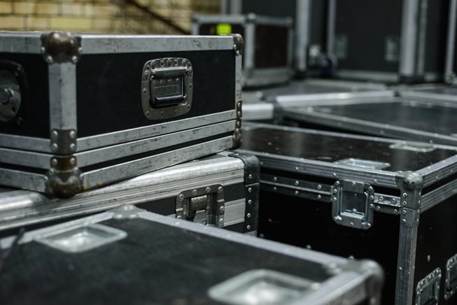 Stacked heavy-duty black road cases with reinforced metal corners for mobile gear transport.